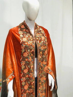 #Orange Mannequin wearing a vibrant orange shawl with floral patterns on a plain background