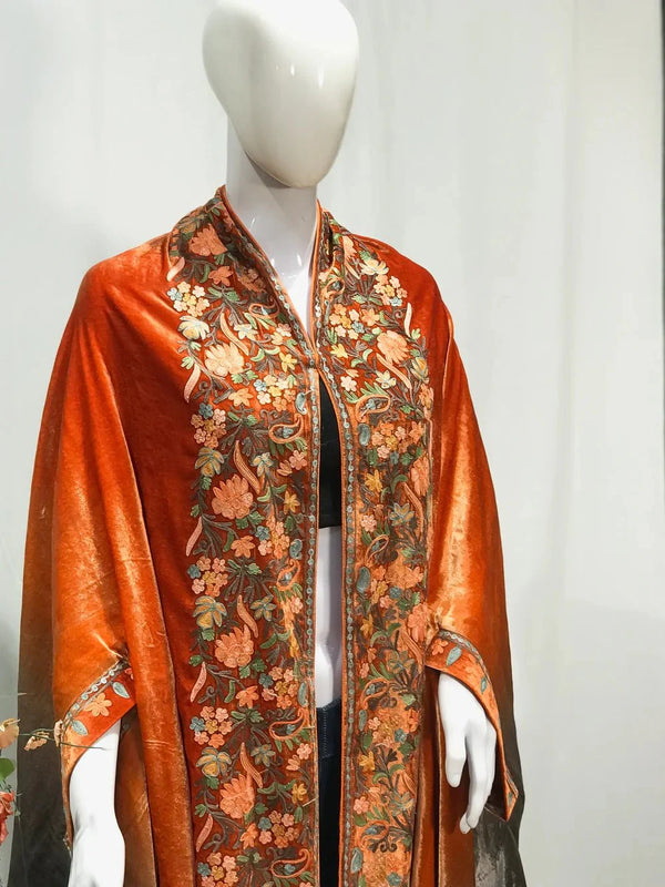 #Orange Mannequin wearing a vibrant orange shawl with floral patterns on a plain background