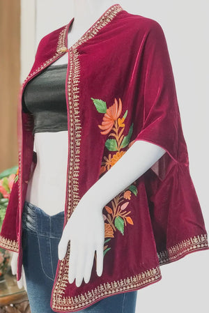 Maroon embroidered jacket over a black top and blue jeans on a mannequin.