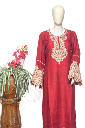 #Red dress with gold embroidery on a mannequin next to a potted plant on a white background