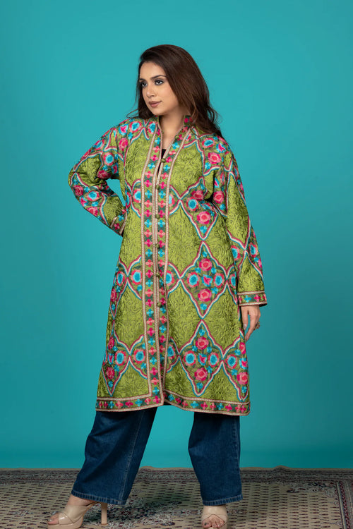 Woman wearing a colorful embroidered kurta with blue pants against a teal background
