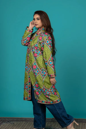 Woman wearing a colorful patterned green dress against a teal background