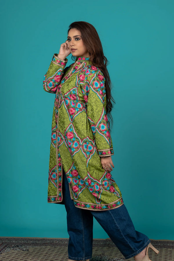 Woman wearing a colorful patterned green dress against a teal background
