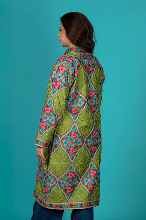 Woman wearing a colorful patterned coat against a teal background