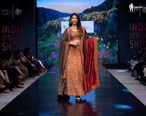 Model walking on a runway in a traditional outfit at the India Designer Show event.