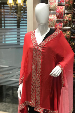 Red traditional outfit with intricate patterns on a mannequin in a store setting.